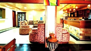 Um hall com sofás estampados, uma mesa de recepção e um vaso decorativo.