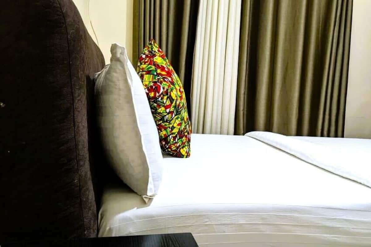 Una habitación de hotel con cama, almohada y cortinas.