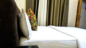 Una habitación de hotel con cama, almohada y cortinas.