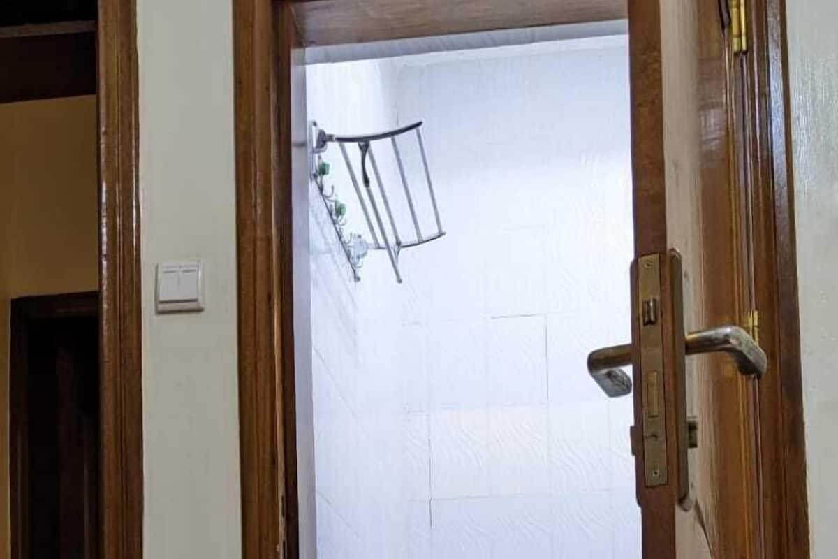 Un baño con inodoro blanco, ducha y perchero para toallas.