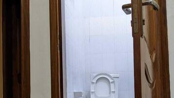 Een badkamer met een wit toilet, een douche en een handdoekrek.