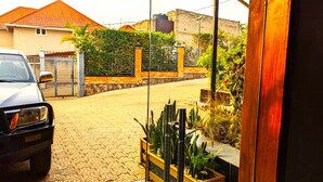 A entrada gradeada com um carro estacionado, acessível por um caminho de paralelepípedos.