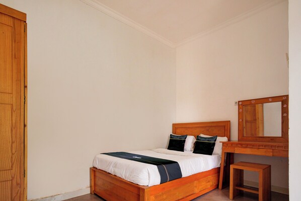 A bedroom with a wooden bed, a small bedside table, and a mirror on the wall.
