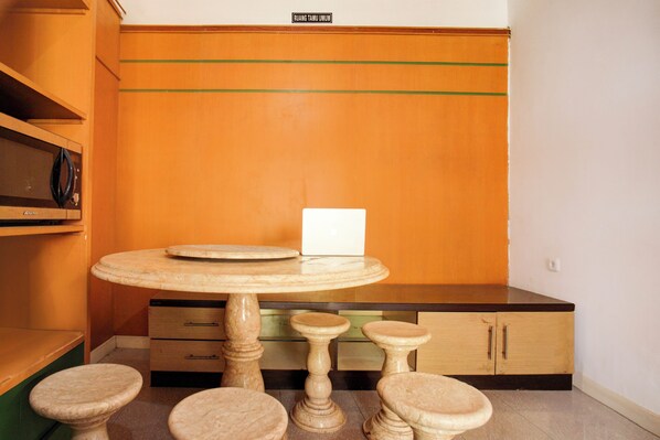 Una habitación con una mesa redonda, cuatro taburetes, un armario y un cartel en la pared.