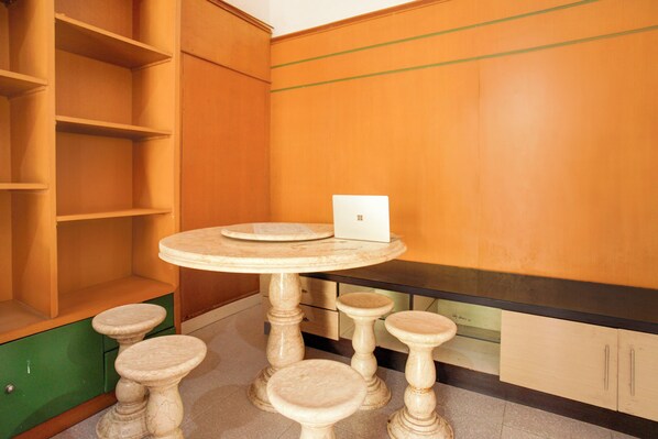 A room with a round table, four stools, a laptop, and wooden cabinets. - Hotel O Twin Kostel (Palembang)