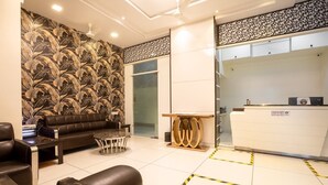 A reception area with a sofa, a small round table, and a reception desk. - Hotel Laaiba Residency (Mumbai)