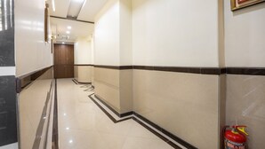 A hallway with a fire extinguisher on the right, a door at the end, and a patterned floor. - Hotel Laaiba Residency (Mumbai)