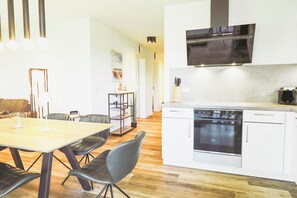 A modern kitchen with a built-in oven and a dining area with a table and chairs.