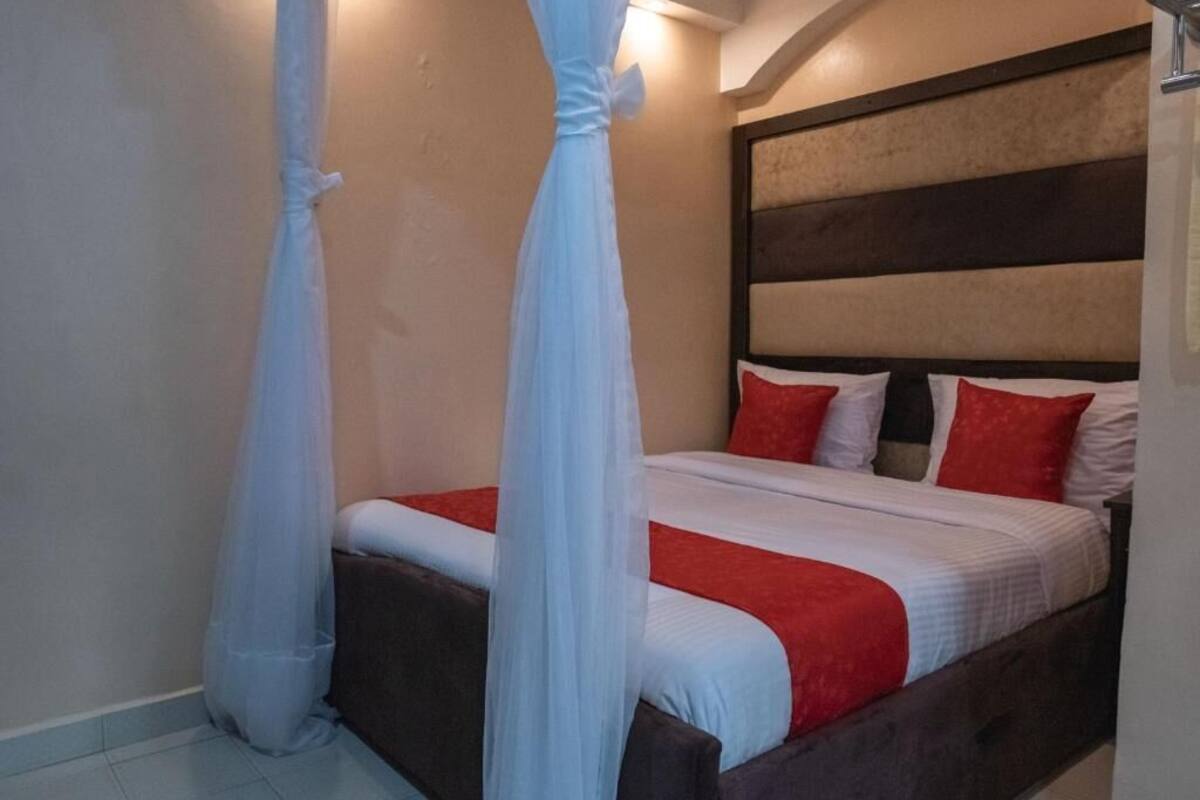 A bedroom with a bed, white curtains, and a headboard with horizontal stripes.