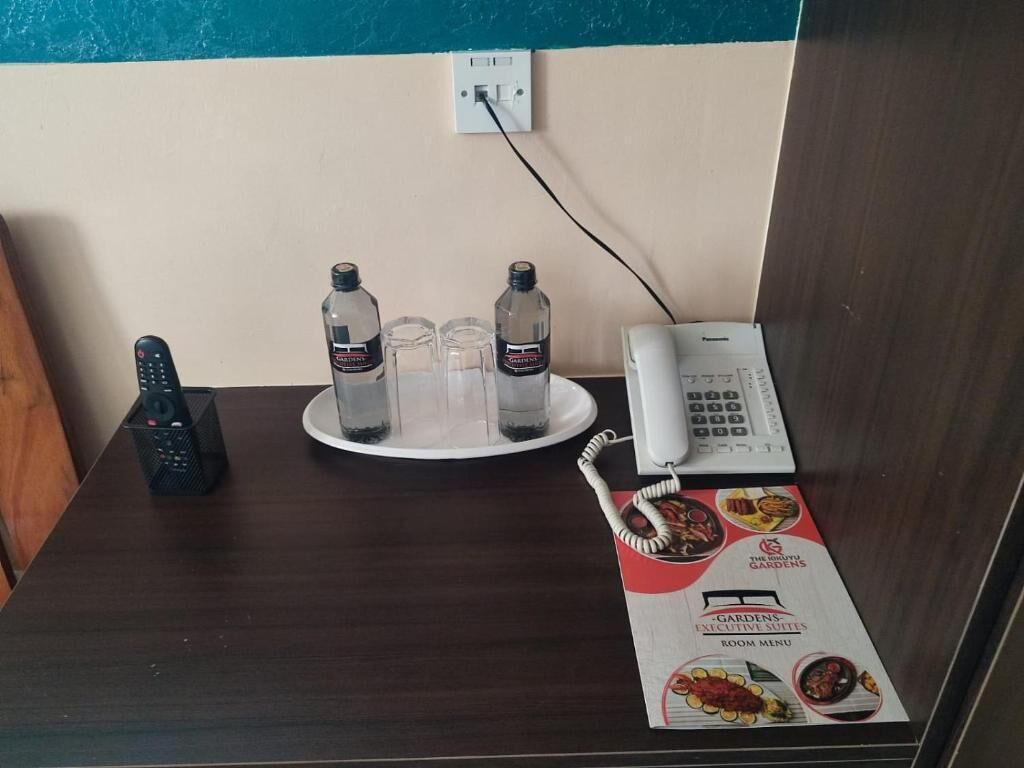 Un comptoir de réception d’hôtel avec un téléphone, deux bouteilles d’eau, une télécommande et un menu.