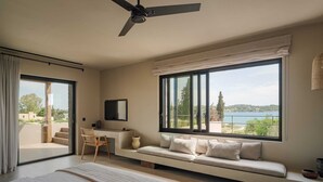 Ein Schlafzimmer mit einem großen Bett, einem Schreibtisch, einem Stuhl und einem Fenster mit Seeblick.