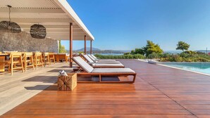 A wooden deck with lounge chairs and a pool, overlooking a scenic landscape.
