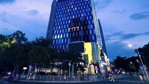 Un gratte-ciel moderne et imposant, doté d’une façade en forme de grille et de fenêtres illuminées.