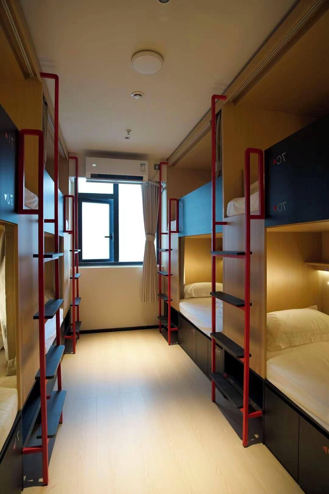 A train compartment with bunk beds, a window, and an air conditioning unit.