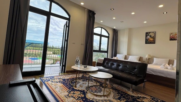 A hotel room with a large window, a sofa, a bed, and a small table. - Beachside Bliss Homestay (Phu Quoc)