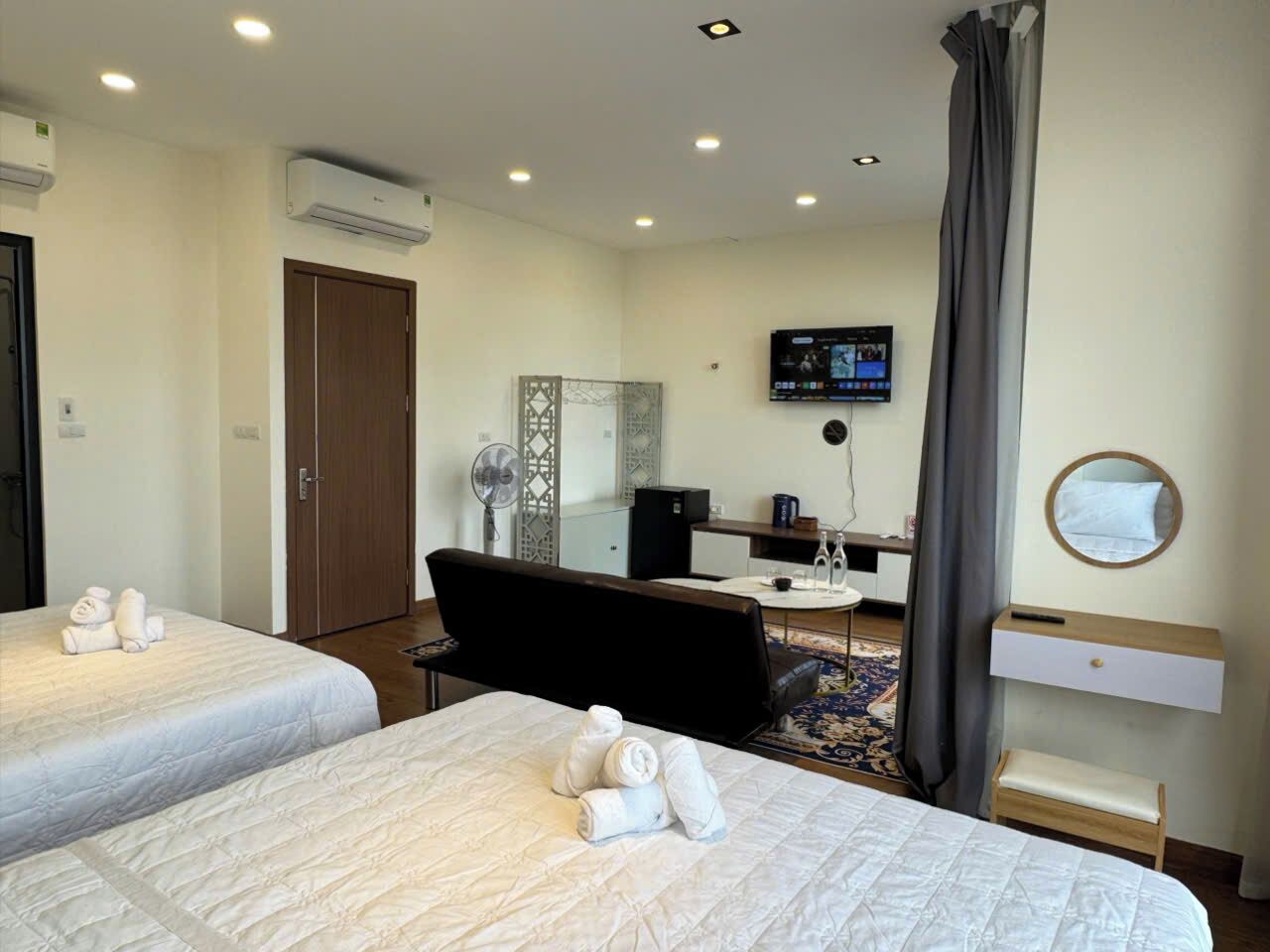 A hotel room with two beds, a desk, a chair, a TV, and a mirror.