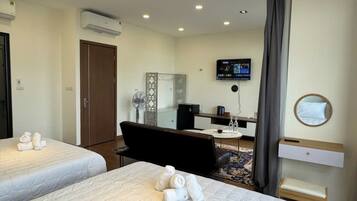 A hotel room with two beds, a desk, a chair, a TV, and a mirror.