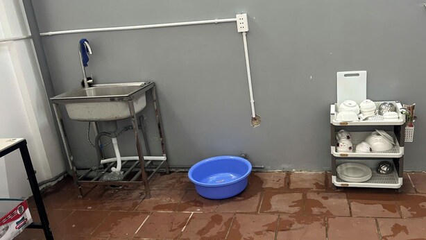 A kitchen area with a sink, a blue basin, and a dish rack with various kitchenware. - Beachside Bliss Homestay (Phu Quoc)