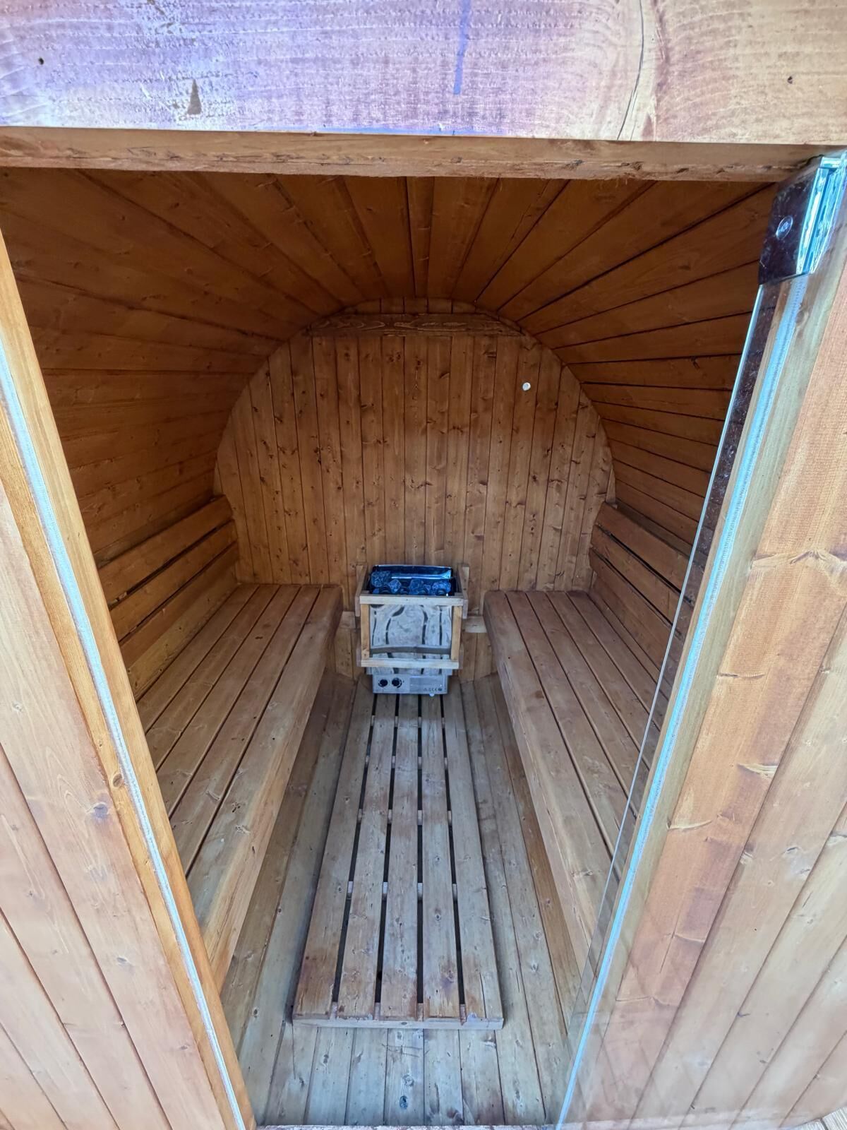 A wooden sauna with a bench and a small table in the center.