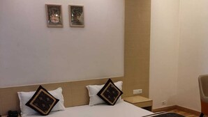 Une chambre d’hôtel avec un lit, deux tables de chevet, une chaise et deux tableaux encadrés au mur.