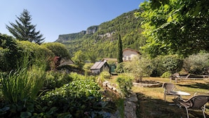 A garden with a pond, chairs, and a house with a sloped roof. - Logis Hotel L'Embarcadère (Nantua)