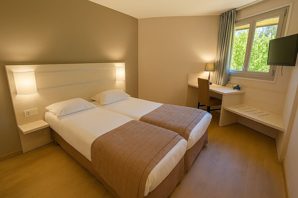Ein Hotelzimmer mit zwei Betten, einem Schreibtisch, einem Stuhl, einem Fernseher und einem Fenster mit Vorhängen.