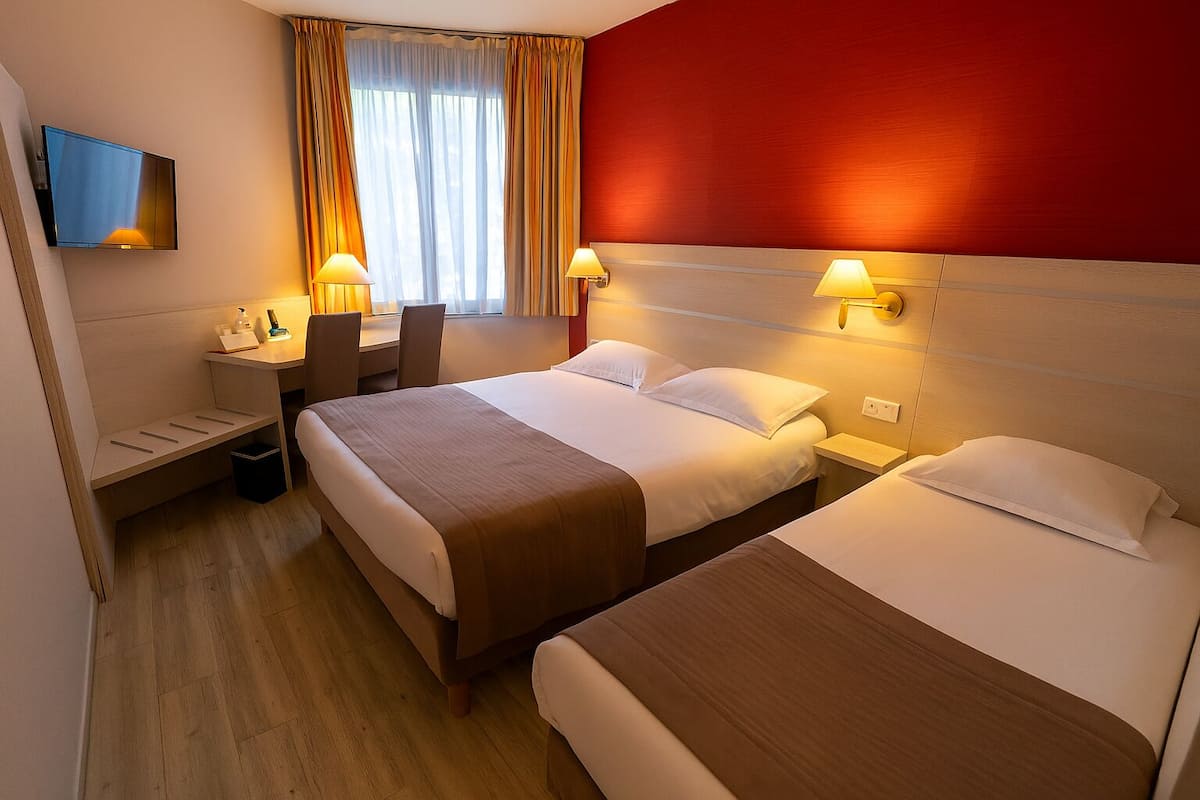 Ein Hotelzimmer mit zwei Betten, einem Schreibtisch und einem Fernseher.