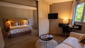 A modern hotel room with a bed, a desk, a chair, and a sofa. - Logis Hotel L'Embarcadère (Nantua)