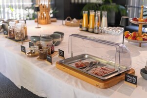 Montaje de bufé con una variedad de alimentos, que incluye una estación de carnes, bebidas y frutas.