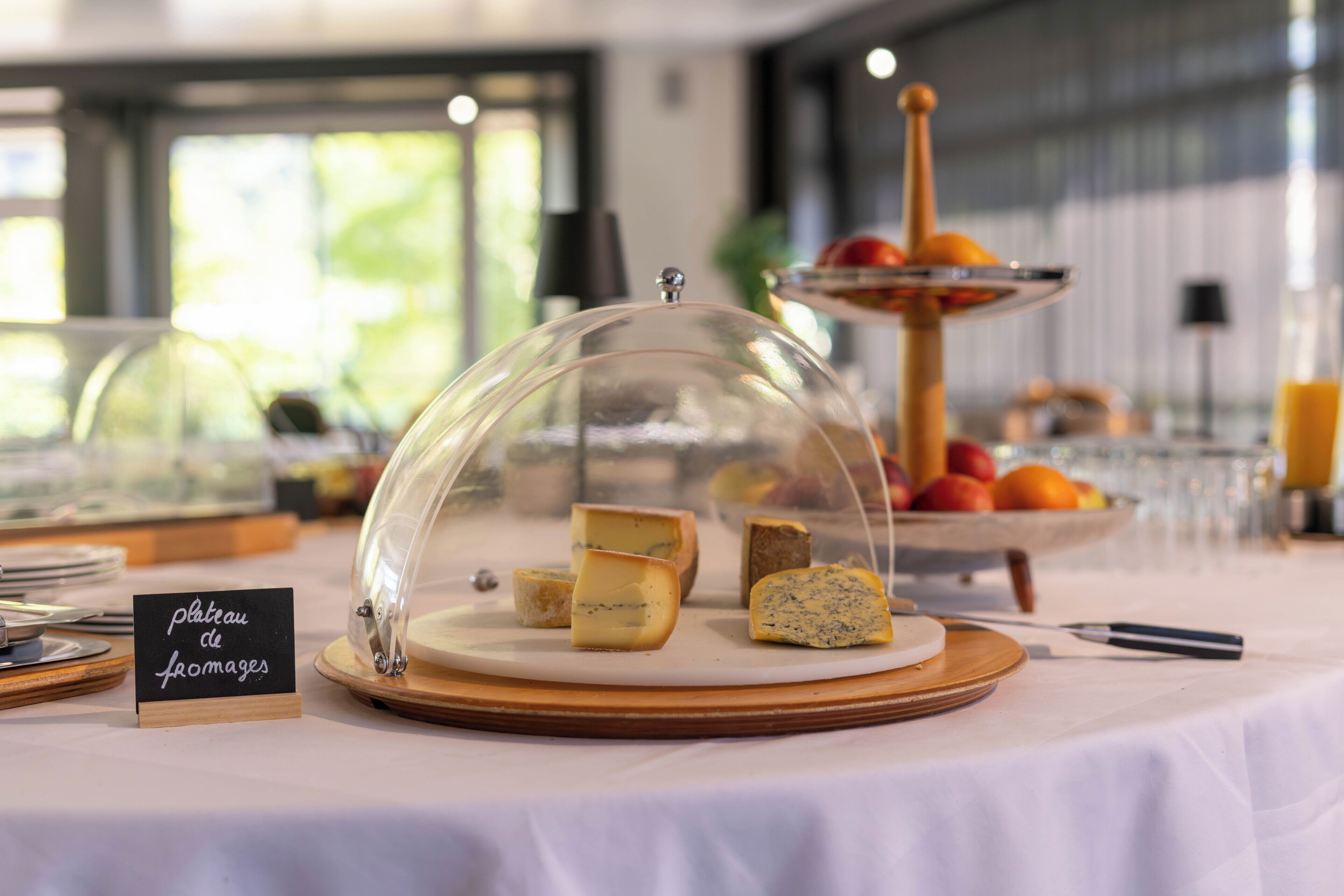 A cheese display with a sign reading "plateau de fromages" on a table with a white tablecloth.