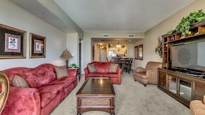 A living room with a red sofa, a coffee table, and a television on a wooden cabinet.