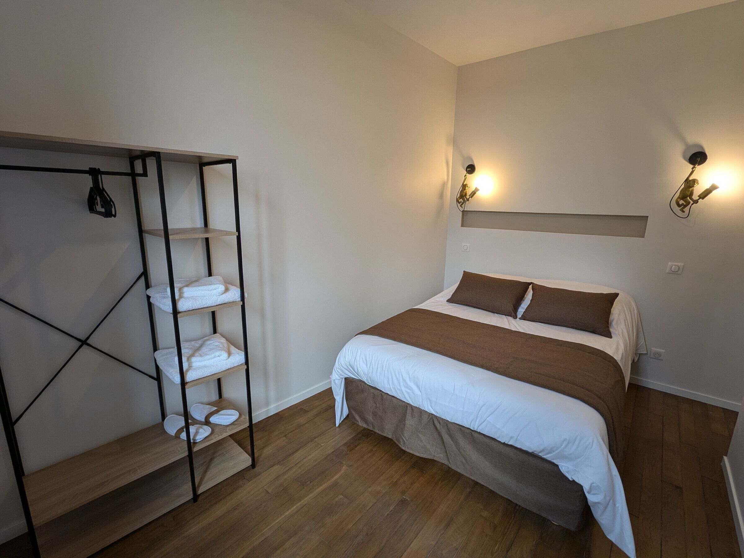 A bedroom with a bed, a wooden floor, a built-in wardrobe, and wall-mounted lighting.