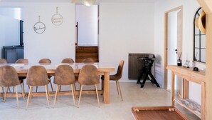 A dining area with a long wooden table, six chairs, and a ceiling light fixture.