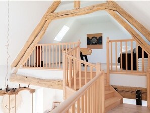 A wooden staircase with a simple railing, leading to a loft bedroom with a bed and a dartboard on the wall. - Domaine Renovated farm with SPA, 15 sleeps, private parking, near Paris (Lorcy)
