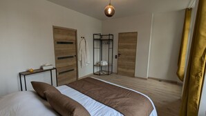 A bedroom with a bed, wooden wardrobe, and a small table with a tissue box.