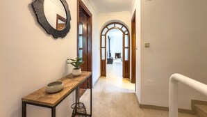 A hallway with a wooden console table, a potted plant, and a mirror.