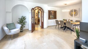 A spacious living area with a dining table, chairs, a sofa, and a potted plant.