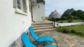 A stone staircase leading to a white building with a blue chair on the steps.