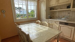 A kitchen with a dining table, chairs, a window, and tiled walls.