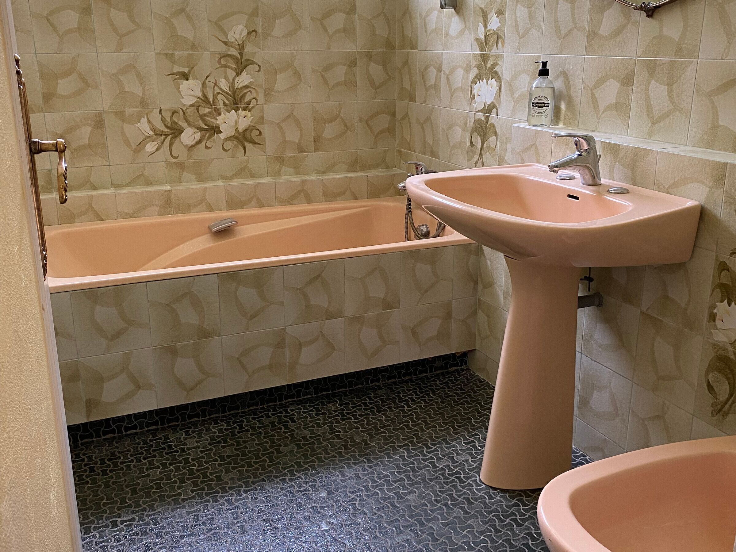 A bathroom with a bathtub, sink, and patterned tiles.