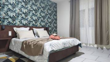 A neatly made bed with a patterned bedspread, a brown headboard, and a geometric rug.