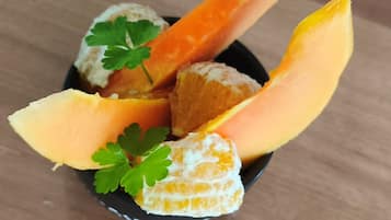 En skål med skiver af cantaloupe melon og appelsinstykker, pyntet med persille.