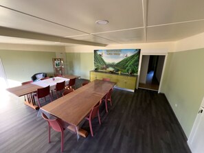 Un salón de conferencias con una larga mesa de madera, sillas rojas, un armario amarillo y un mural en la pared.