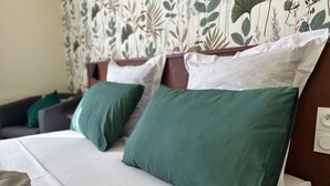 Un lit avec des oreillers verts et blancs, un oreiller marron et un couvre-lit blanc.