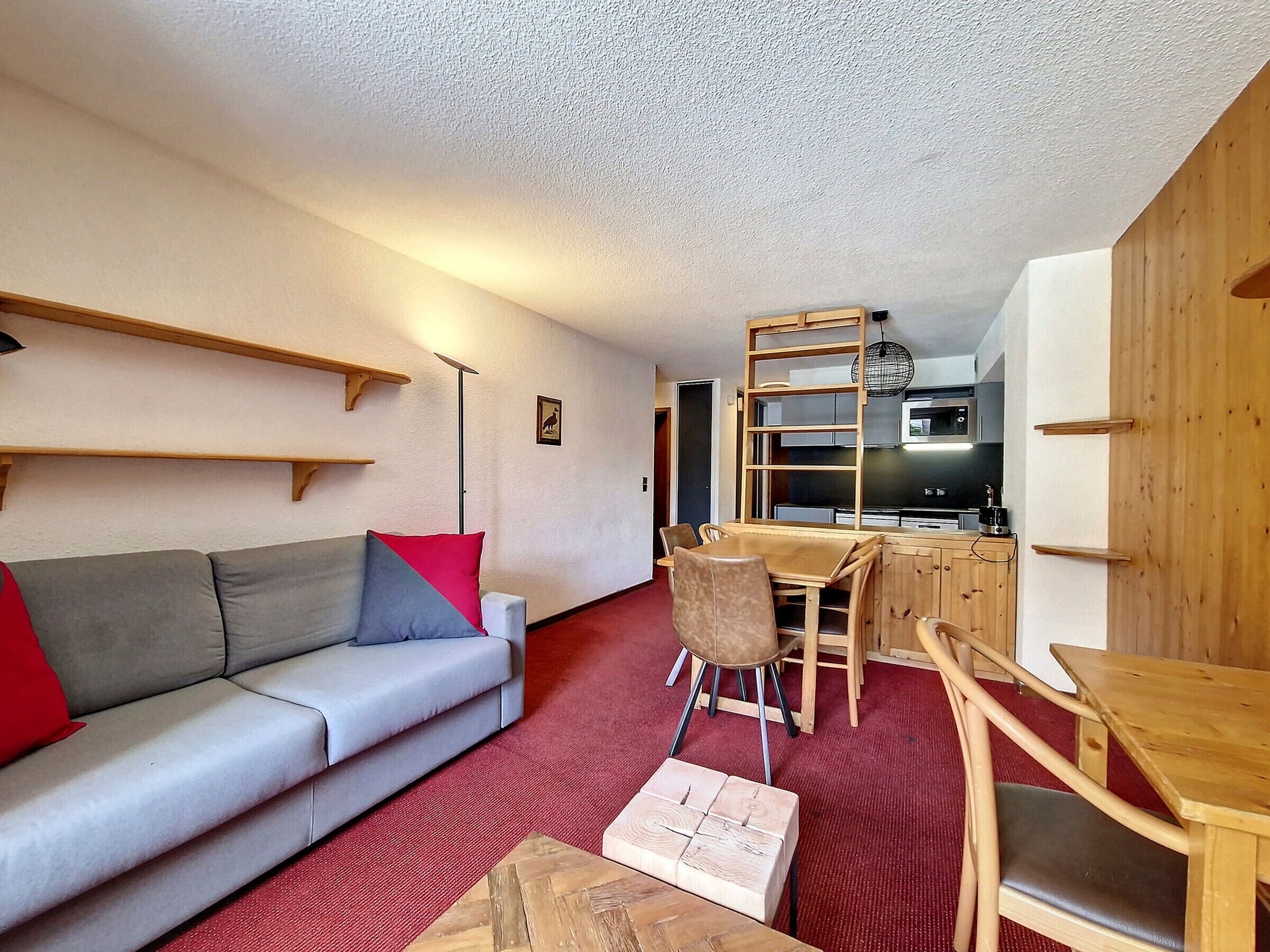 Un espacio habitable compacto con sofá, mesa de comedor y zona de cocina.