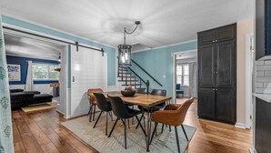 A dining area with a wooden table, black chairs, and a chandelier.