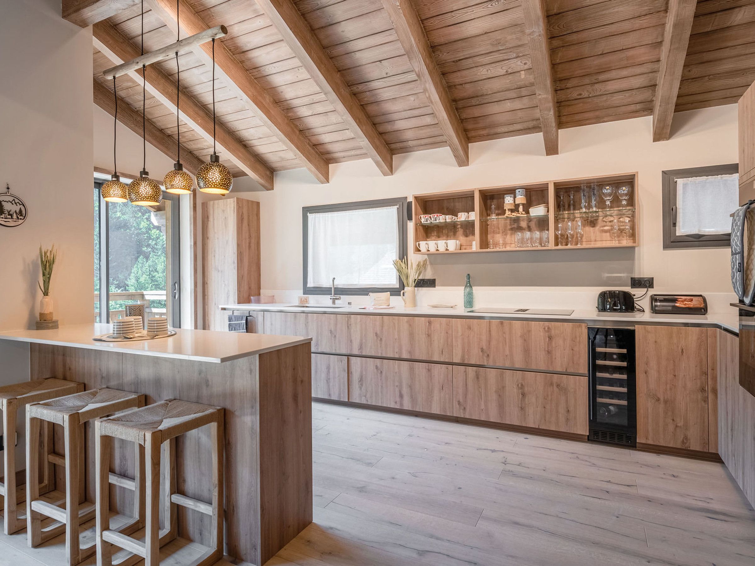 Una cocina moderna con vigas de madera, una isla central con taburetes y armarios empotrados.
