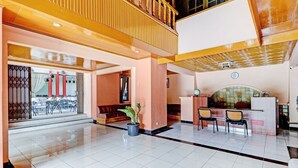 Eine geräumige Lobby mit hoher Decke, einem Empfangsbereich und einer Sitzecke mit Sesseln und einer Couch.