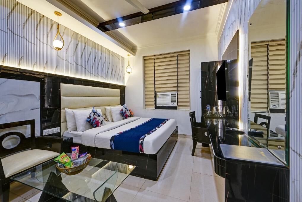 A modern hotel room with a large bed, a glass coffee table, a desk, and a TV.