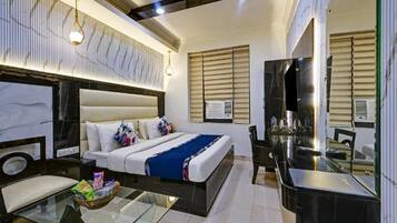 A modern hotel room with a large bed, a glass coffee table, a desk, and a TV.